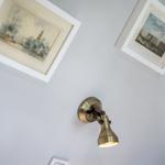 Two framed pictures on the wall and a wall lamp with a brass shade.