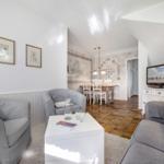 Living and dining area with gray sofas, white coffee table, and wooden floor.