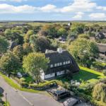 Thatched-roof house surrounded by greenery and trees.