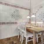Dining room with wooden table, white chairs, and tiled walls.