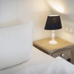 Schlafzimmer mit Bett, Nachttisch und Lampe unter Dachschräge.