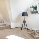Dachgeschosszimmer mit Schlafcouch, Stehlampe und Wandregal.
