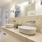 Badezimmer mit zwei Waschbecken, Steinwand und Badewanne.