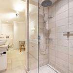 Dusche mit Glaswand, Waschbecken und Spiegel im Badezimmer