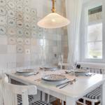 Dining room with white table, chairs, and decorative tiles on the wall.