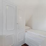Bedroom with double bed, white closet, and wall lamp