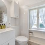 Bathroom with sink, toilet, and window with curtains.