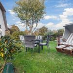Garden with seating group and beach chair. House with sliding door and tree.