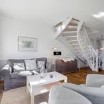 Living room with gray sofa, white table, and spiral staircase.