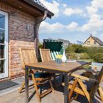 Terrasse mit Holztisch und Stühlen, grüner Hinterhof und Sitzmöbel