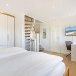 Schlafzimmer mit Bett, Schrank und Arbeitsplatz mit Fernseher.