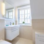 Badezimmer mit Waschbecken, Spiegel und Fenster