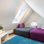Dachgeschosszimmer mit Schlafcouch, Dachfenster und runder Fensteröffnung.