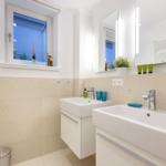 Zwei Waschbecken mit Spiegeln und Fenster im Badezimmer.