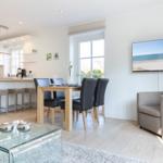 Moderne Küche, Essbereich und Wohnzimmer mit TV und Fenster.