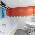 Bad mit Badewanne, Waschbecken und Fenster mit Blick auf Wald.