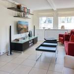 Wohnzimmer mit rotem Sofa, Fernseher und Bücherregal an der Wand.