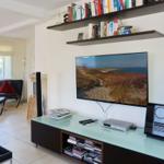 Wohnzimmer mit TV, Bücherregalen und Sitzgelegenheit.