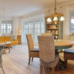 Dining area with round table and chairs, living area with sofa and windows