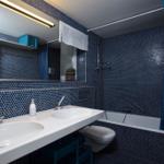 Bathroom with blue mosaic tiles, shower, bathtub, and double sink.