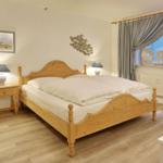 Bedroom with wooden bed, nightstand, and window with curtains.