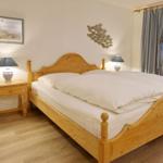 Bedroom with wooden bed, nightstand, and window with curtains.