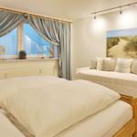 Bedroom with double bed, sofa, and window view.