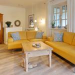 Two yellow sofas with blue cushions around a wooden table.