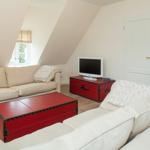 Living room with cream sofas, red trunk table, and TV on red trunk.