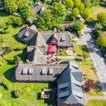 Village house with thatched roof, garden, and terrace with red umbrella.