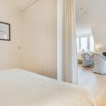 Schlafzimmer mit Blick auf Wohnbereich mit Sofa und Stühlen
