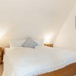 Schlafzimmer mit Doppelbett, zwei Nachttischen und einer Wanddekoration.