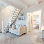 Wohnbereich mit Sofa, Treppe und Blick in Schlafzimmer.