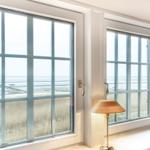 Zwei Fenster mit Meerblick und einer Stehlampe auf Fensterbank.