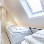 Schlafzimmer mit Dachfenster, Bett und Handtüchern.