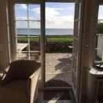 Durch offene Türen blickt man auf einen gepflasterten Hof mit Garten und Meer.