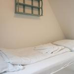 Two beds with white linens and towels against sloped walls.