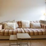 A sofa with checkered upholstery and cushions near a window.