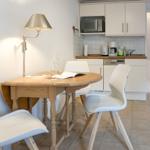 Dining table with three chairs and kitchen area in background.
