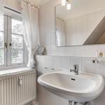 Bathroom with sink, mirror, and window with white curtains.