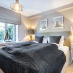 Bedroom with bed, nightstands, and window overlooking greenery.