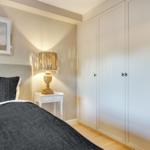 Bedroom with bed, nightstand, and wardrobe. Wall art and lamp are visible.