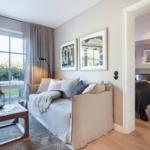 Living area with sofa and garden view. Adjacent room with bed and nightstand.