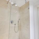 Shower with glass enclosure, showerhead, and handheld shower