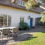 Wohnhaus mit strohgedecktem Dach und blauer Tür. Außenbereich mit Tisch und Stühlen.