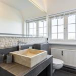 Badezimmer mit Waschtisch, Spiegel und Fenster
