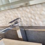 Dusche mit Steinwand und modernem Wasserhahn