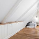 Dachgeschosszimmer mit Bett, Schrank und Holzboden.