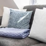 Ein grauer Sofa mit Kissen und einer Decke.