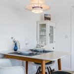Esstisch mit Stühlen, Glas- und Porzellanbesteck, Vase und Decke.